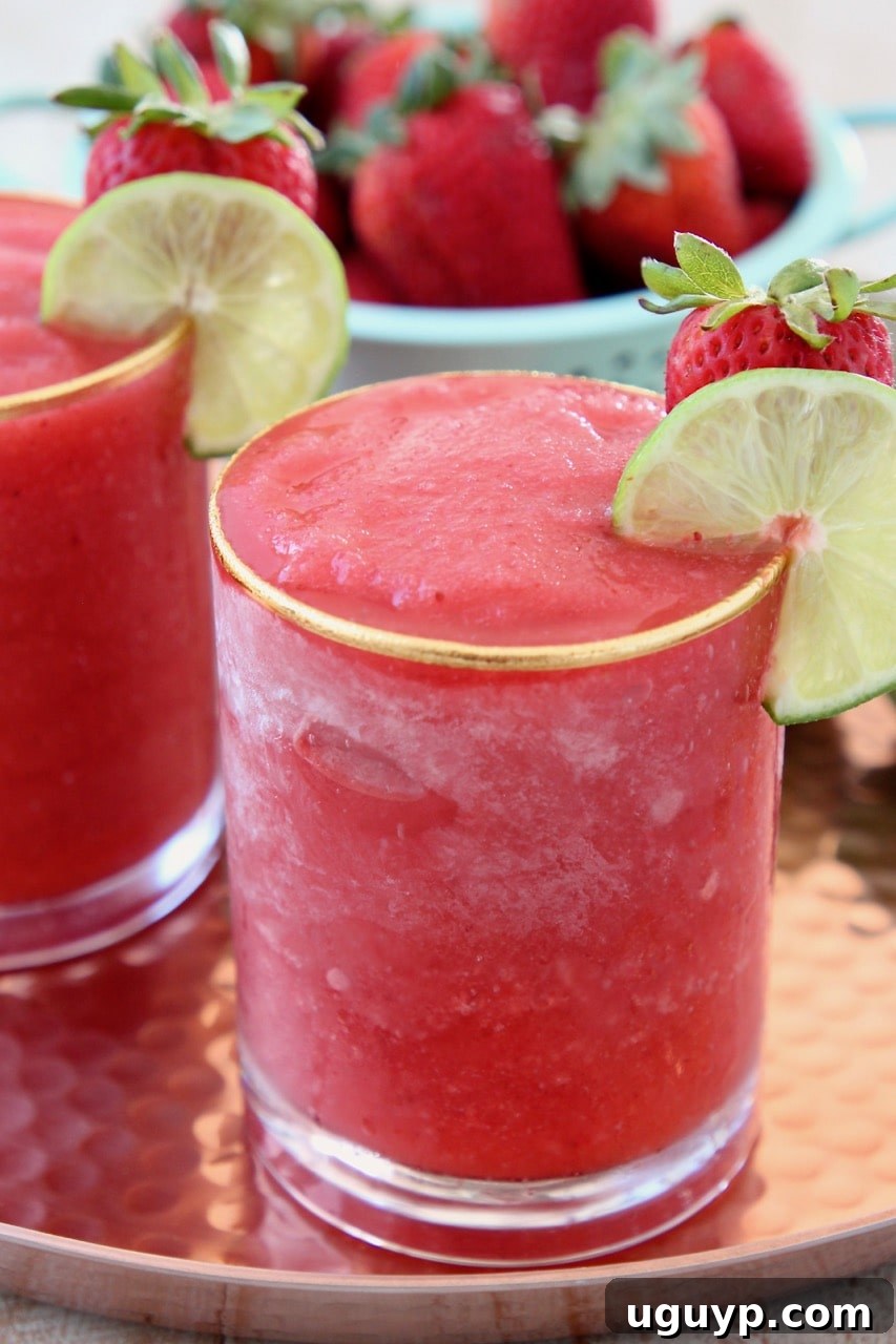 Blended strawberry daiquiri in glass with lime wedge on the side