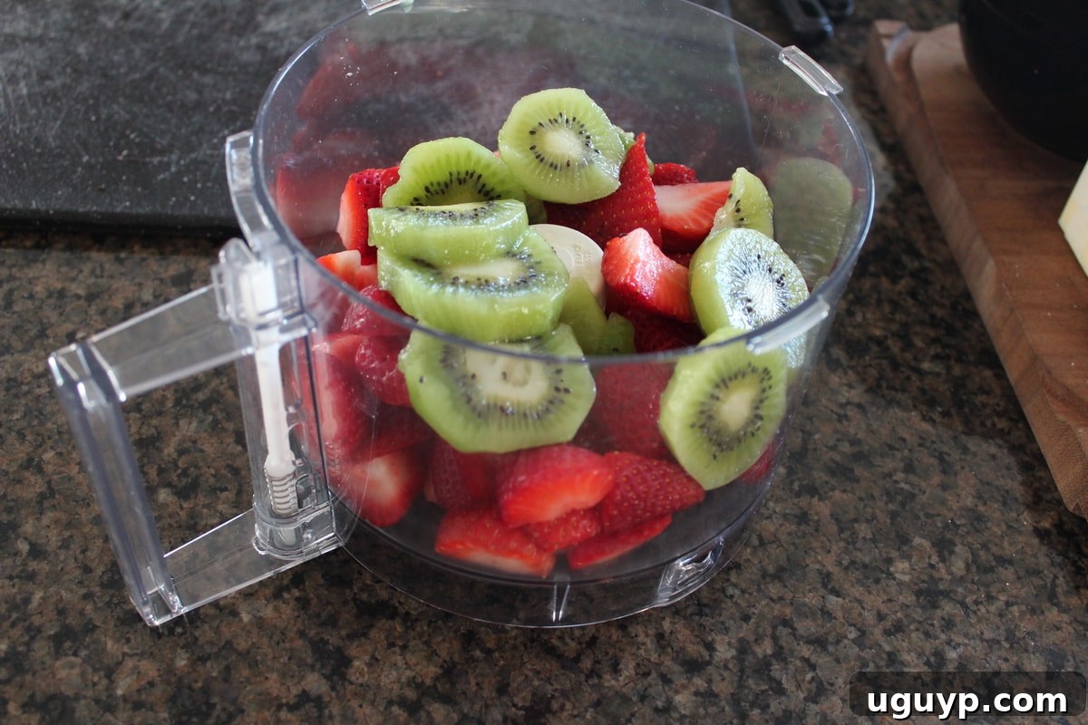 Strawberries and kiwi being pureed in a food processor