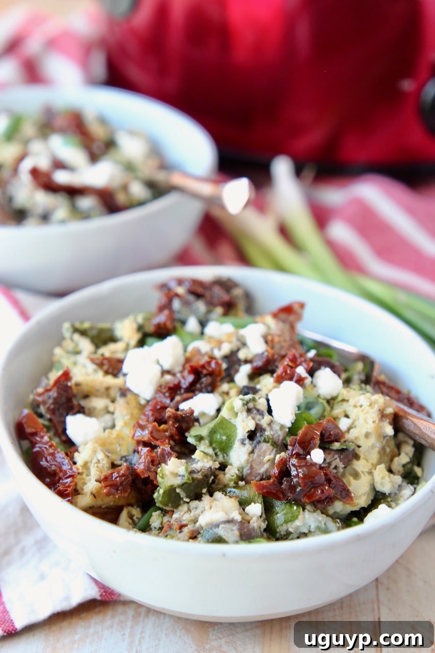 Individual bowls of Greek egg casserole garnished with fresh green onions and vibrant sun-dried tomatoes.