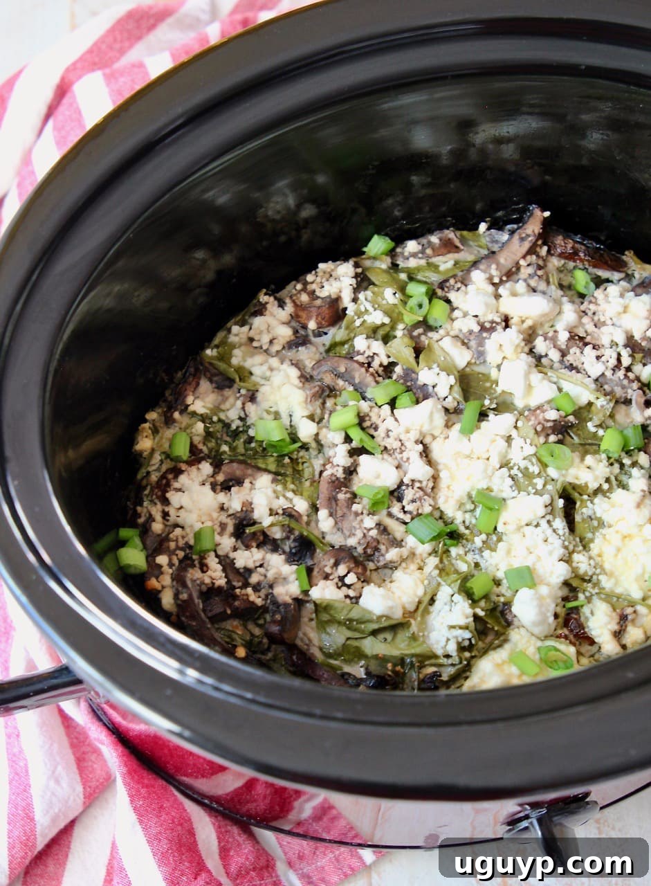 Close-up of a golden crockpot breakfast casserole, topped with melted feta cheese and fresh green onions.