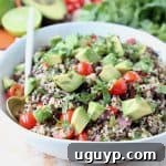 White bowl filled with quinoa salad with diced avocado and tomatoes, showcasing the fresh, vibrant ingredients.