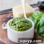 Basil pesto in white marble bowl with small gold spoon in the bowl