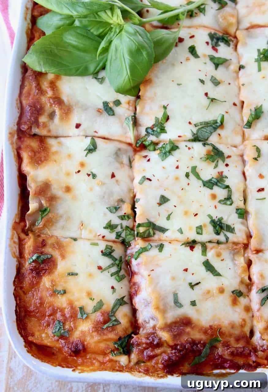 overhead image of lasagna in white casserole dish sliced into pieces