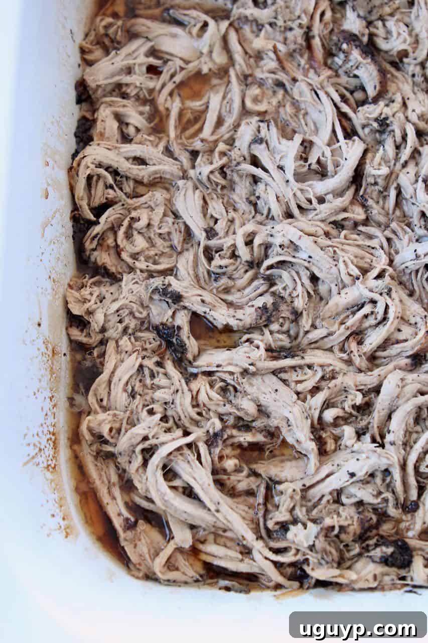 Inside view of a crock pot showing coffee-crusted pulled pork tenderloin simmering in a flavorful sauce.