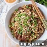 Overhead shot of sliced beef and noodles in bowl with chopsticks on the side