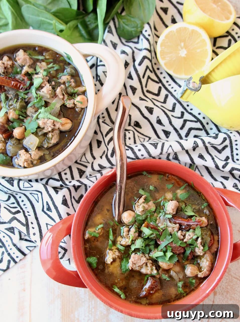 Overhead shot of two bowls filled with ground turkey soup with spinach and chickpeas, garnished with fresh herbs