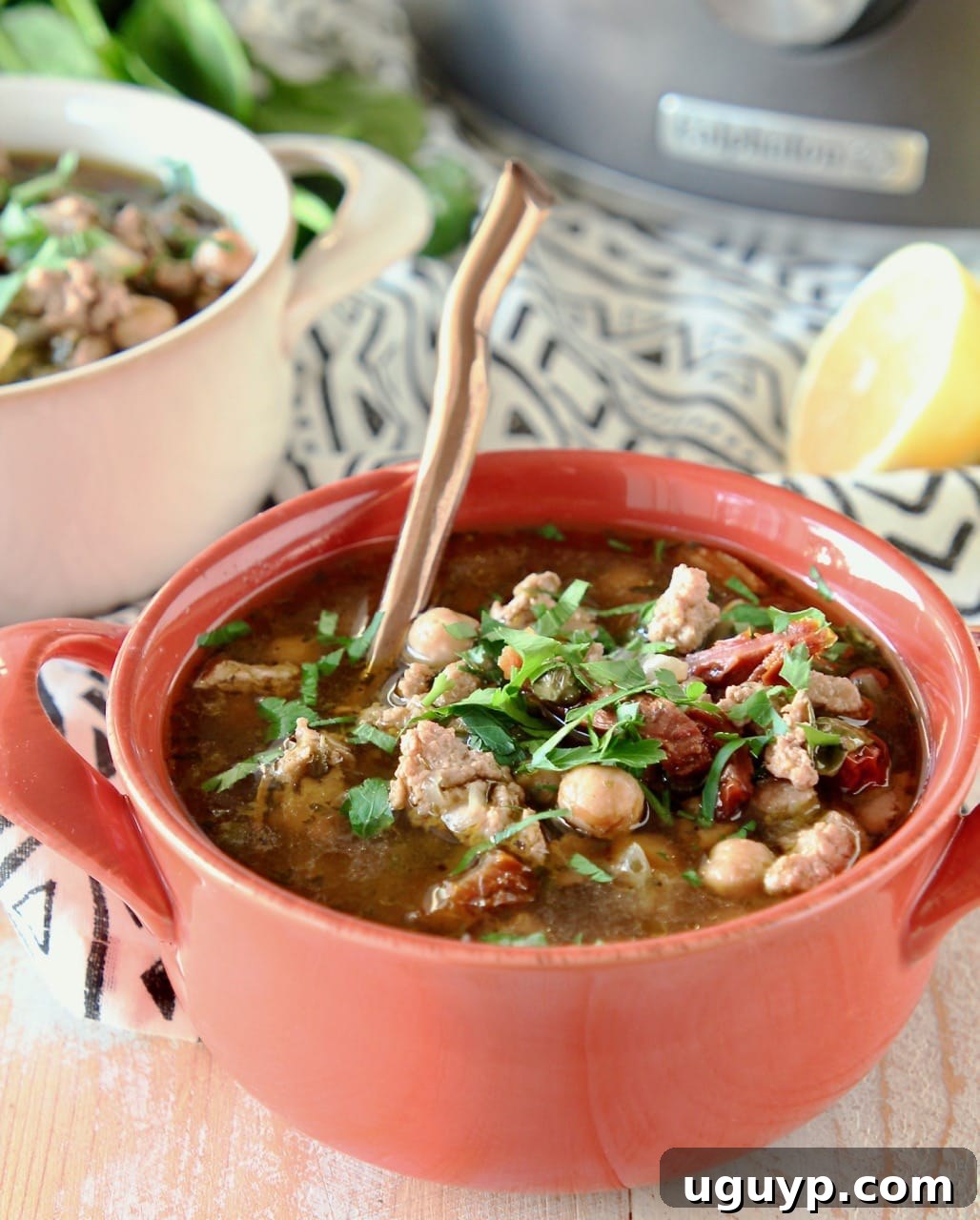 Greek turkey soup with chickpeas and spinach in an orange bowl with a copper spoon, ready to be served