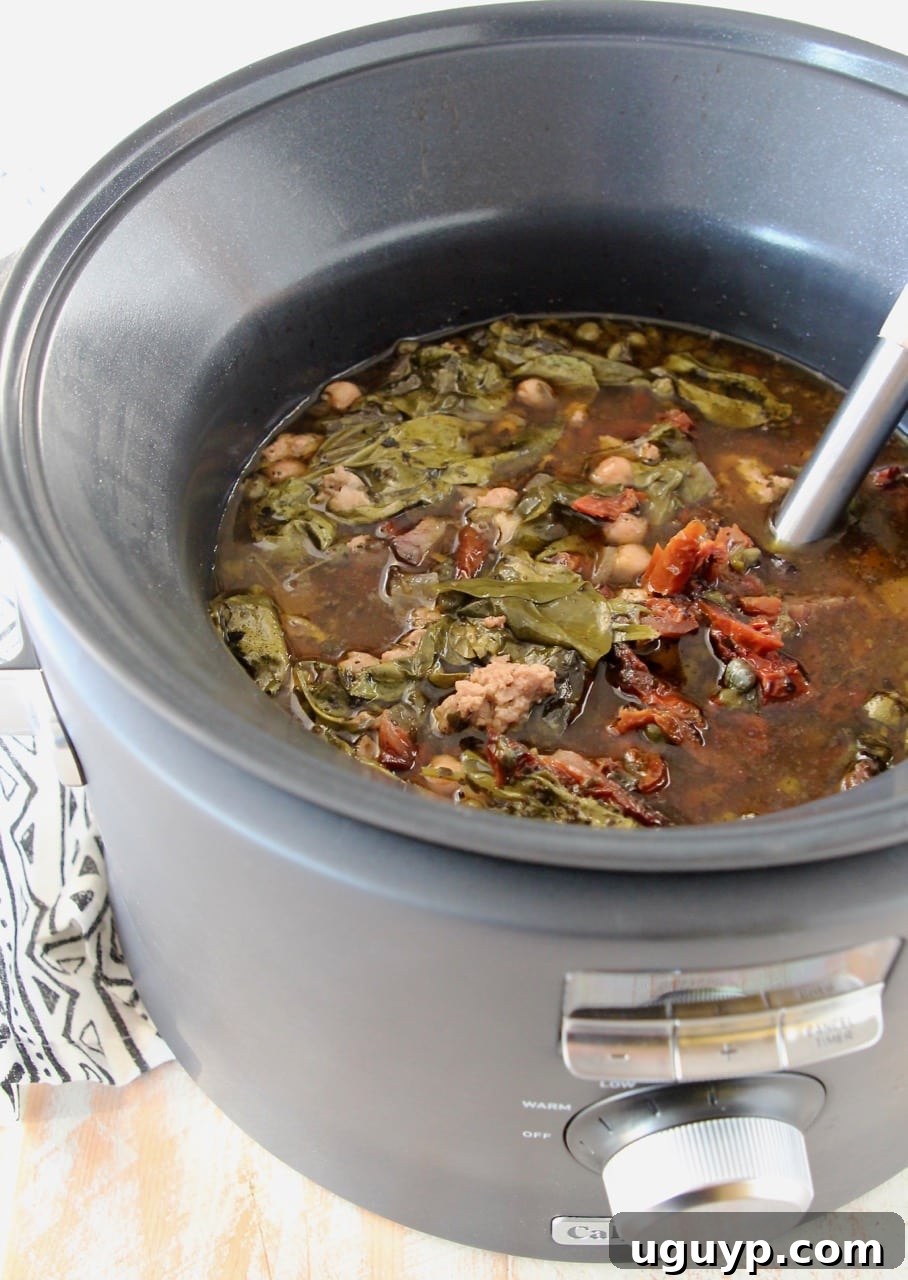 Greek turkey soup with spinach simmering in a slow cooker, steam gently rising