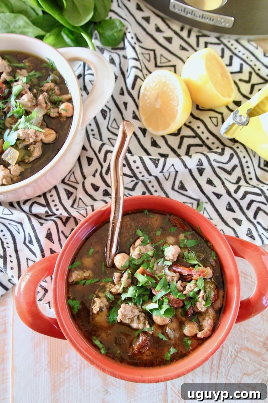 Ground turkey soup with chickpeas and spinach in bowls with sliced lemon on the side, ready to eat