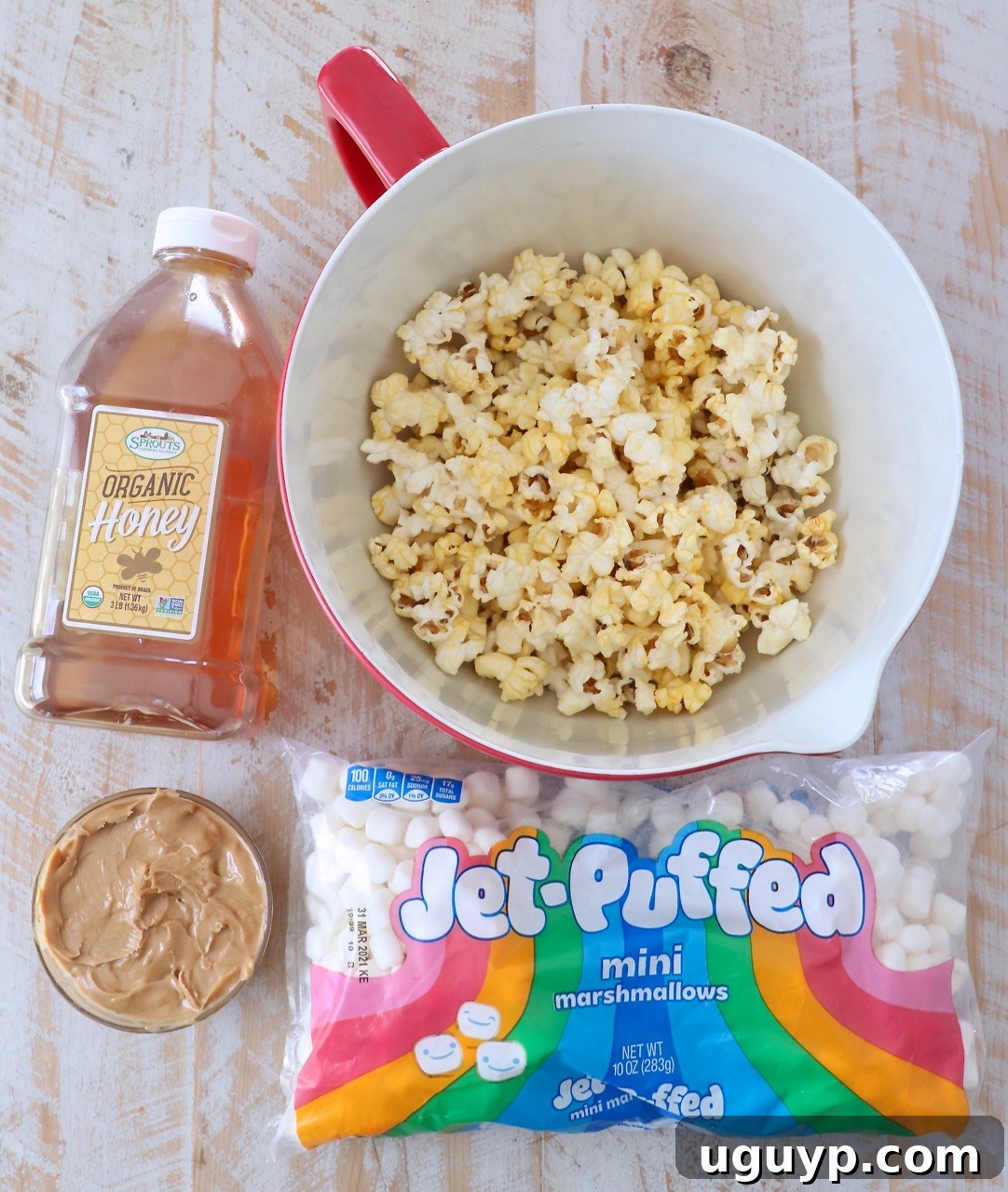 A vibrant collection of ingredients for making Peanut Butter Popcorn Balls, laid out on a kitchen counter.