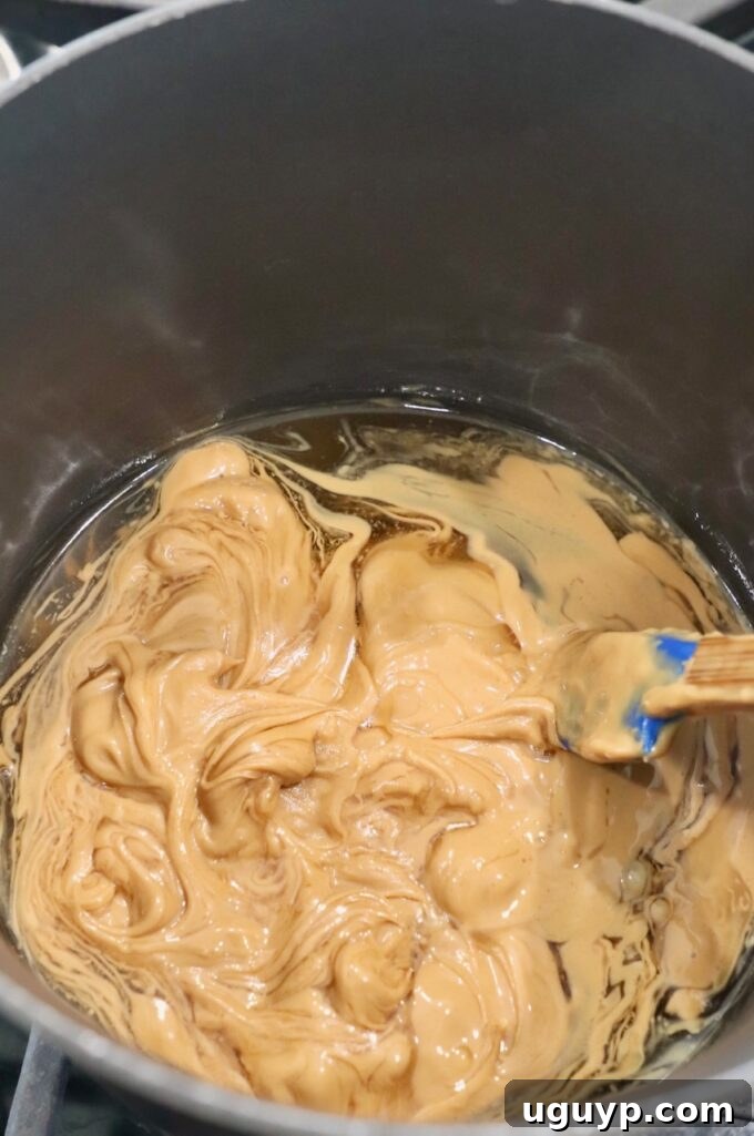 Peanut butter and honey melting together in a saucepan on the stove, forming a smooth base.