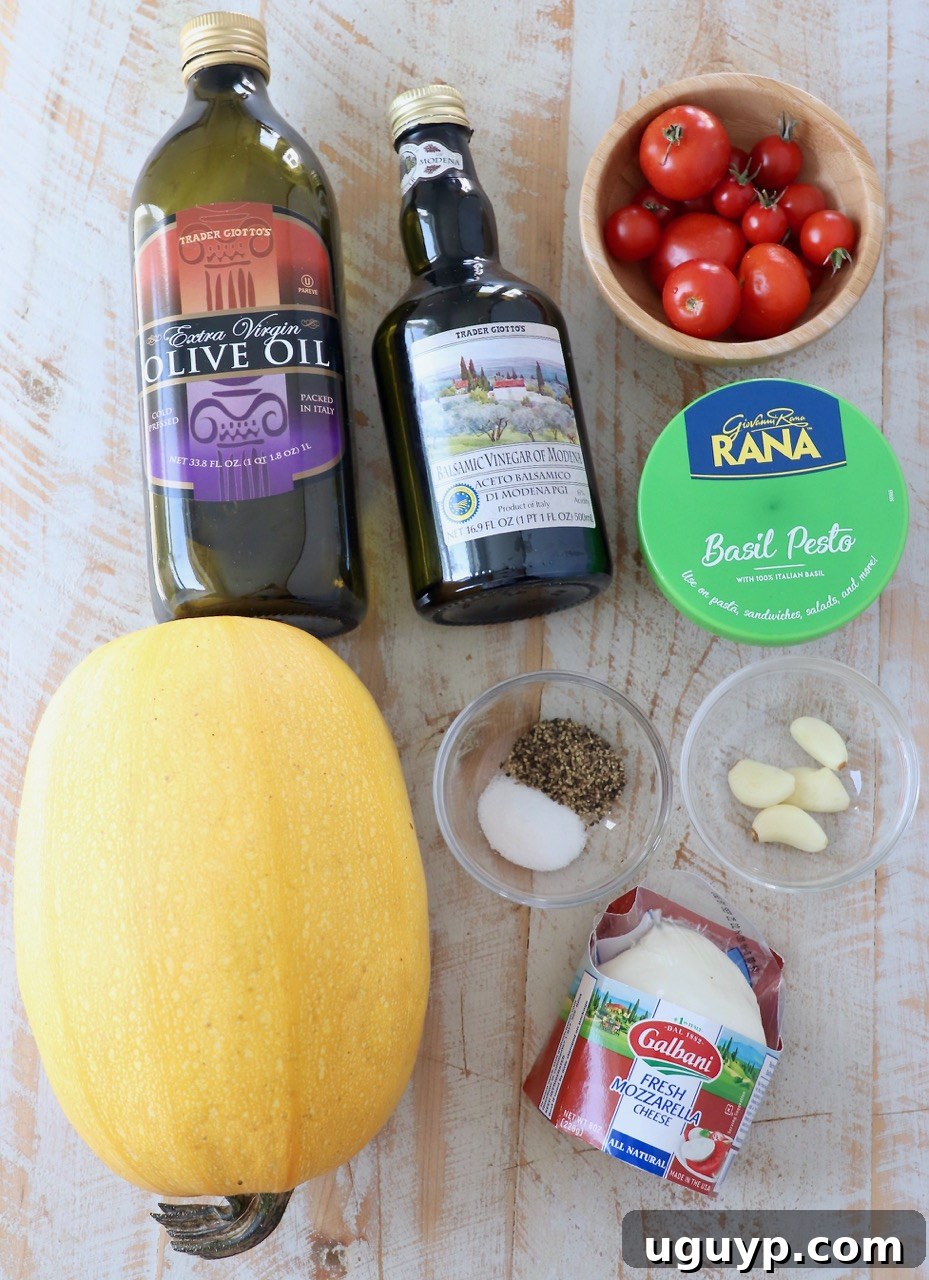 Assortment of fresh ingredients for Caprese Spaghetti Squash, including a whole spaghetti squash, cherry tomatoes, basil, garlic, and mozzarella.
