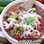 chili in a bowl with a spoon topped with grated cheese