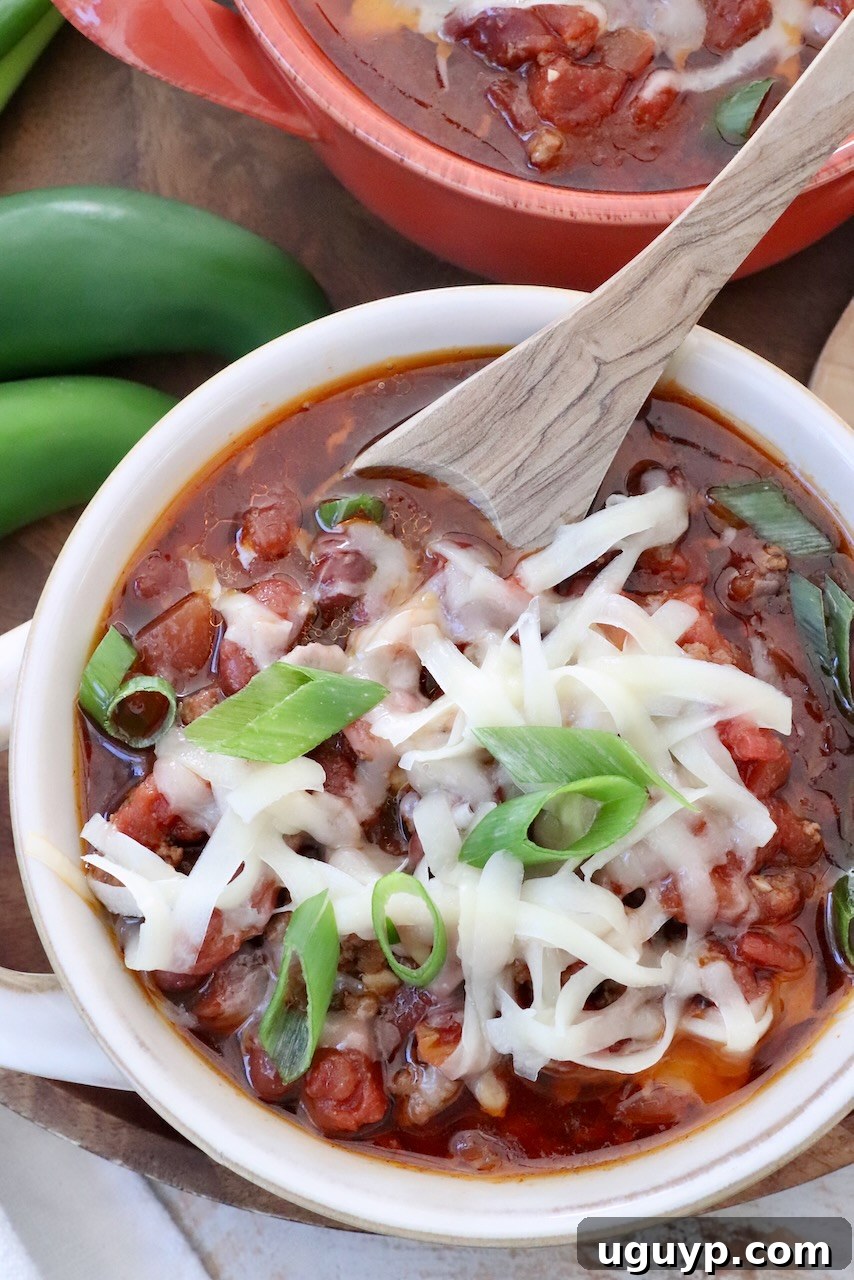 chili in a bowl topped with shredded cheese and diced green onions