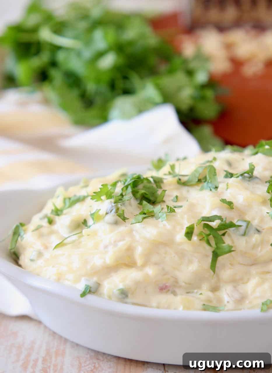 Spaghetti squash tossed with jalapeno cheese sauce in white baking dish, ready to be served.