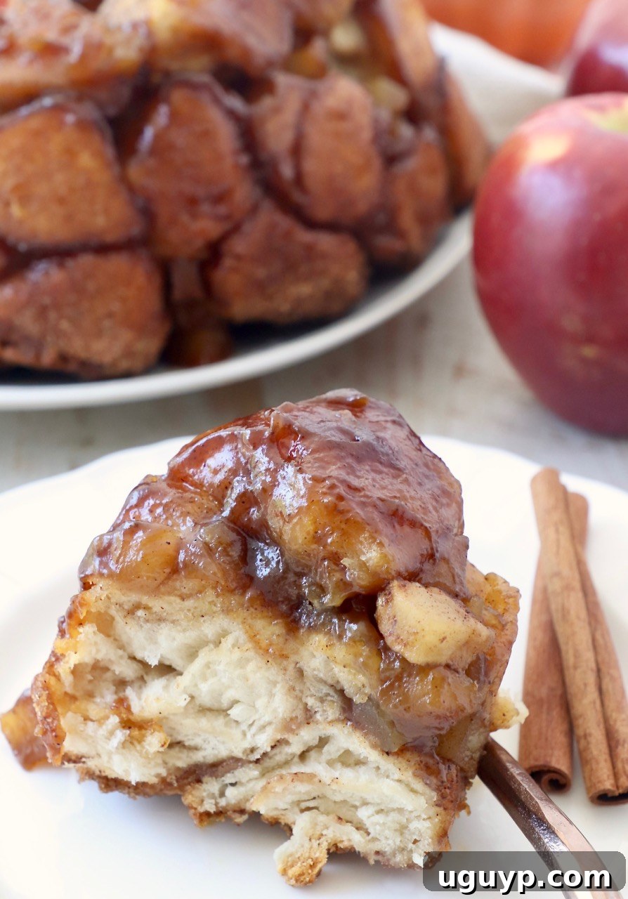 A beautiful slice of Pumpkin Apple Monkey Bread on a plate, garnished with cinnamon sticks, evoking warm fall feelings.