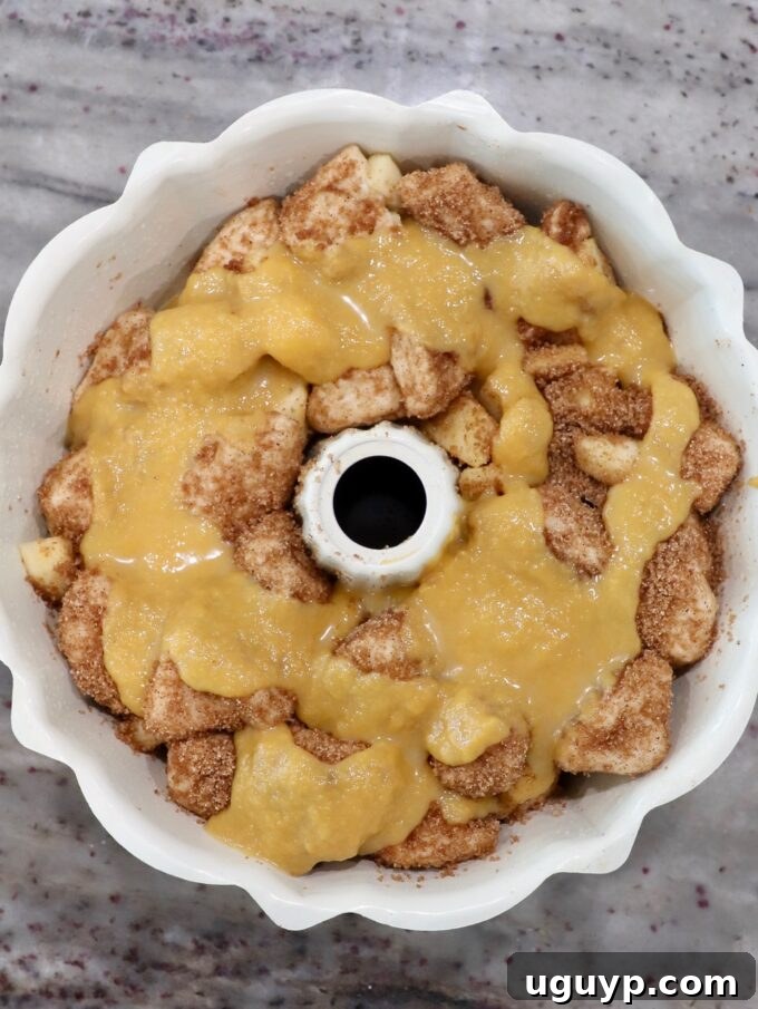 Cinnamon sugar-coated diced biscuit dough in a bundt pan, topped with the remaining pumpkin puree mixture.