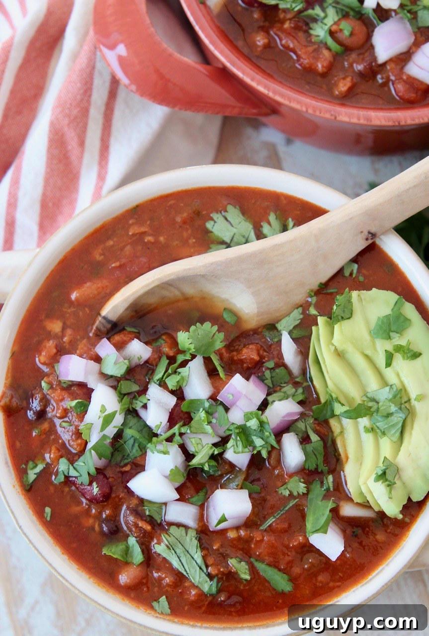 A vibrant bowl of vegan chili, garnished with sliced avocado and fresh cilantro, ready to be enjoyed.