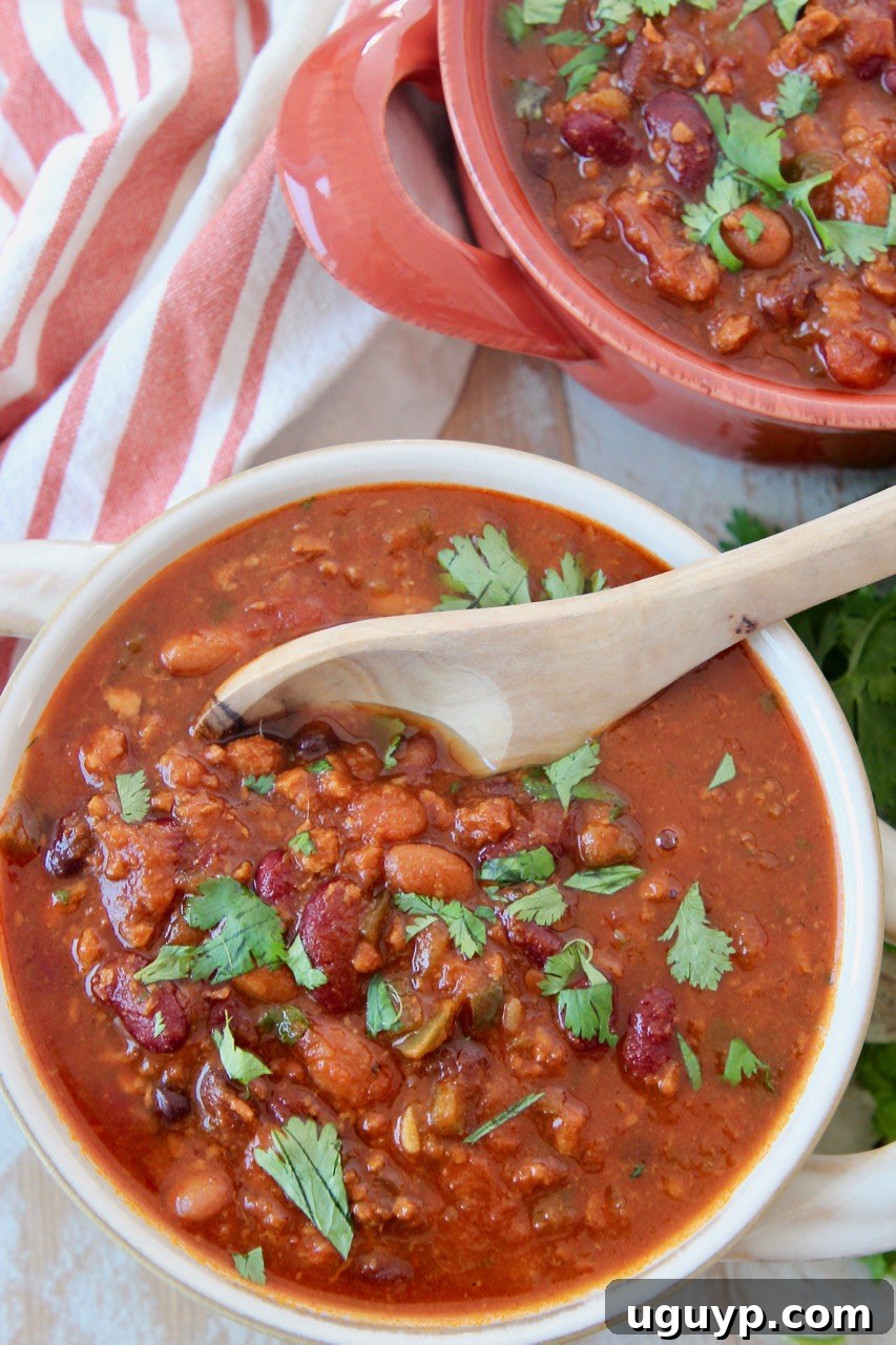A close-up of vegan chili in a bowl with a wooden spoon, showcasing its rich texture and color.