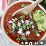 A bowl of rich vegan chili topped with fresh diced onions and creamy sliced avocado, ready to serve.
