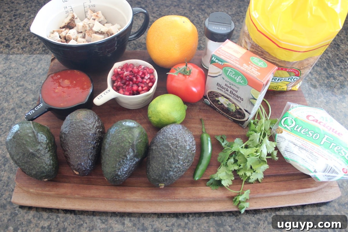 Ingredients for turkey tostadas and pomegranate guacamole laid out on a wooden surface, including avocados, pomegranate, diced turkey, and tostada shells.