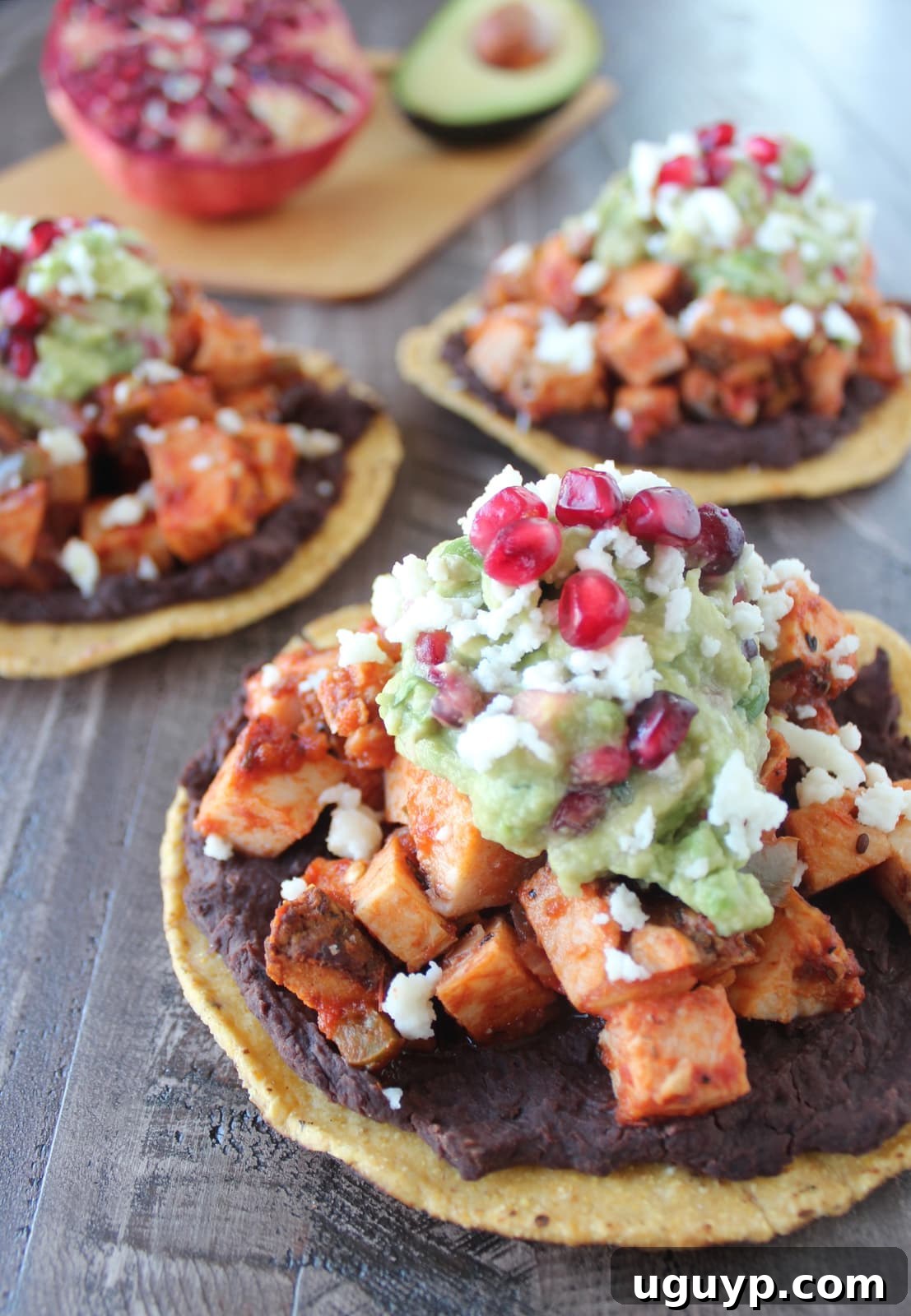 Two turkey tostadas on a wooden board, showcasing their vibrant colors and appealing layers against a slightly blurred background.
