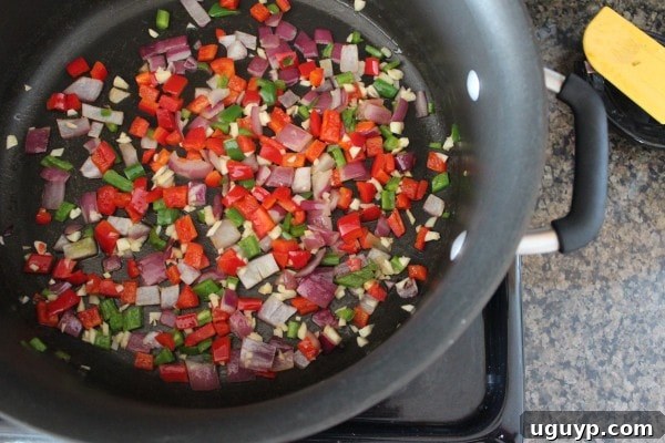 Sautéing onions, bell peppers, garlic, and jalapeños in a large pot.