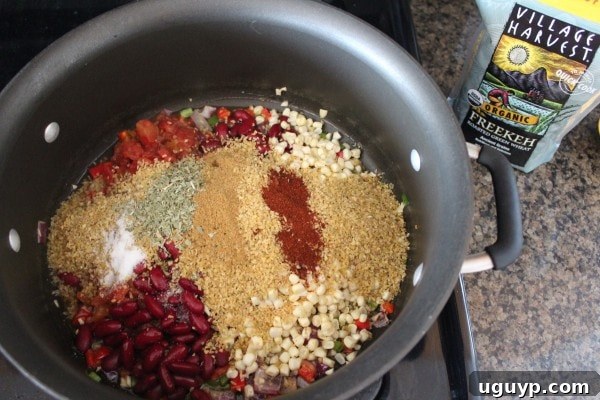 Adding freekeh, corn, diced tomatoes, kidney beans, and Mexican spices to the pot.