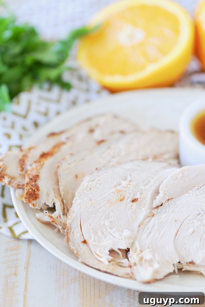 Slices of spice rubbed turkey breast on white plate with side of orange bourbon sauce and sliced orange