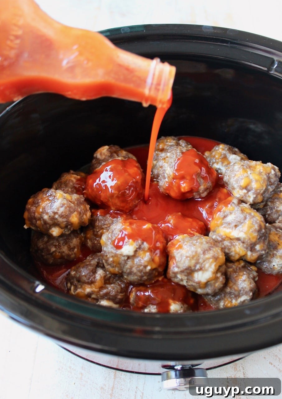 Cheesy Sausage Balls in Crock Pot with Buffalo Sauce Poured into the Crock Pot