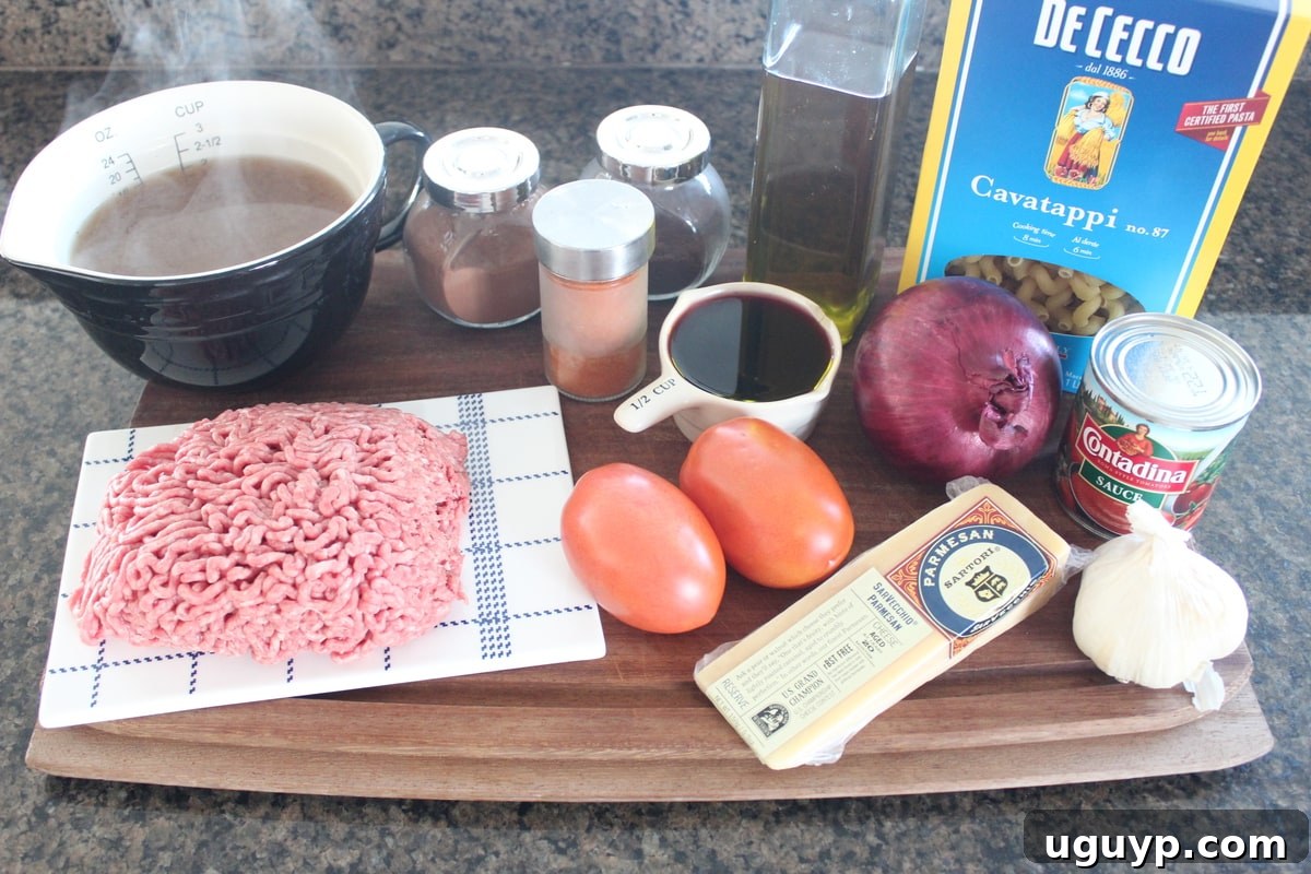 All the fresh ingredients for Mediterranean Spiced Beef and Macaroni laid out on a rustic wooden board, including ground beef, diced tomatoes, macaroni, and various spices.