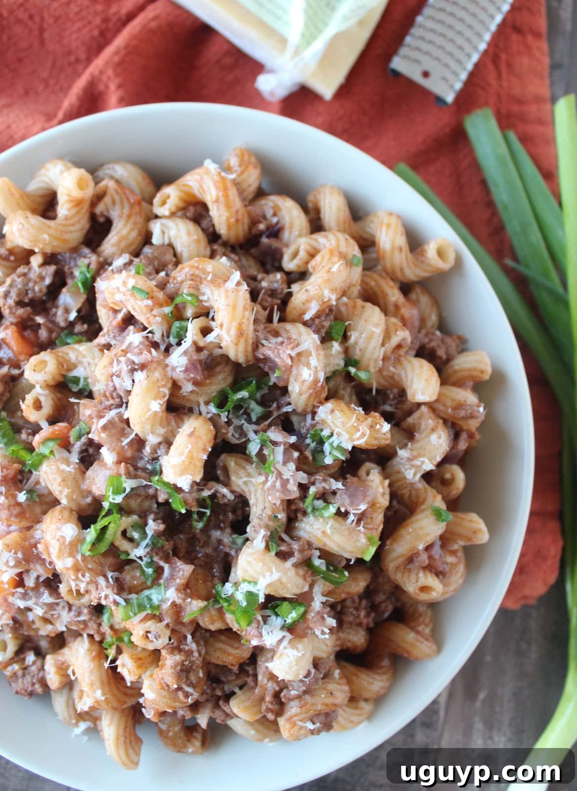 A serving of Mediterranean-spiced beef and macaroni, topped with a generous sprinkle of Parmesan cheese, highlighting the rich texture and appealing presentation.