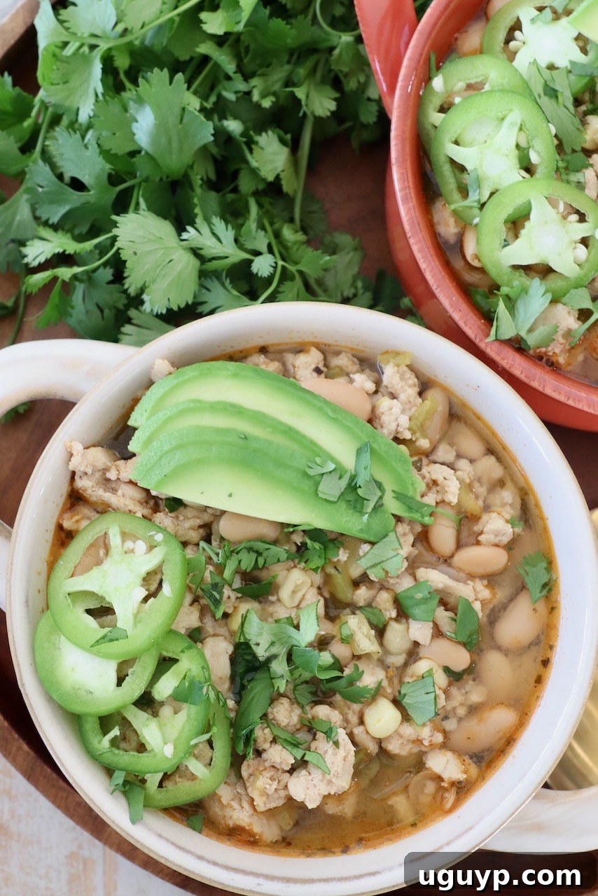 white chicken chili in bowls topped with sliced jalapenos and avocado
