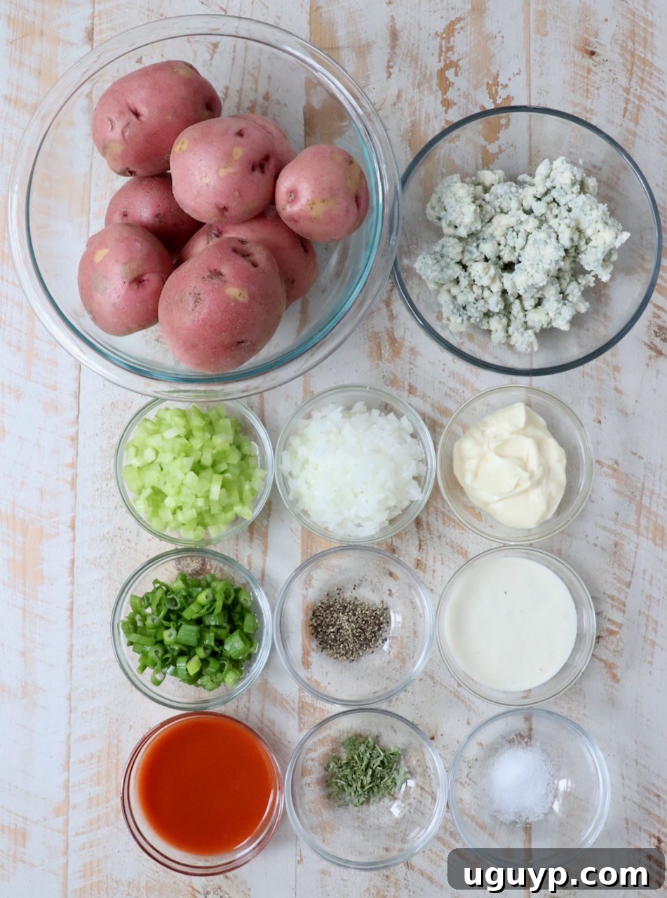 Ingredients for buffalo potato salad neatly arranged in glass bowls on a rustic white wooden board, showcasing fresh and vibrant components.