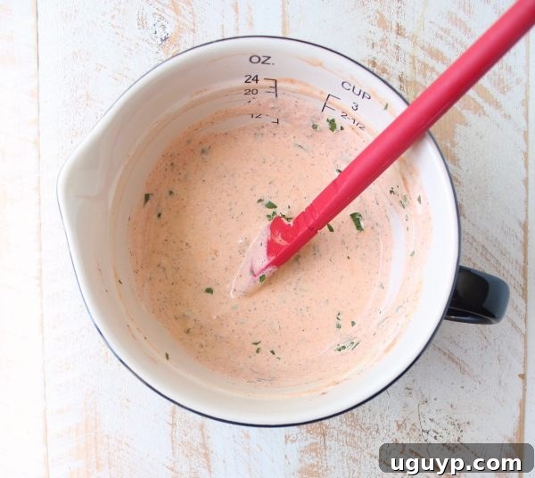 A rich, creamy buffalo sauce dressing mixed in a small white bowl, with a red spatula resting inside, illustrating the perfect consistency.