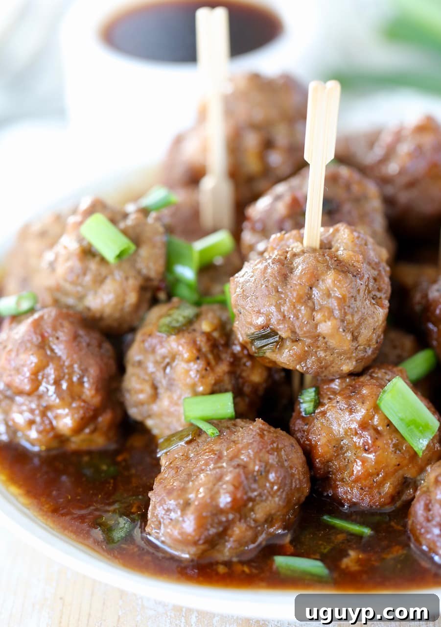 Plate piled high with succulent Korean BBQ meatballs, garnished with fresh green onions and wooden skewers for easy serving.