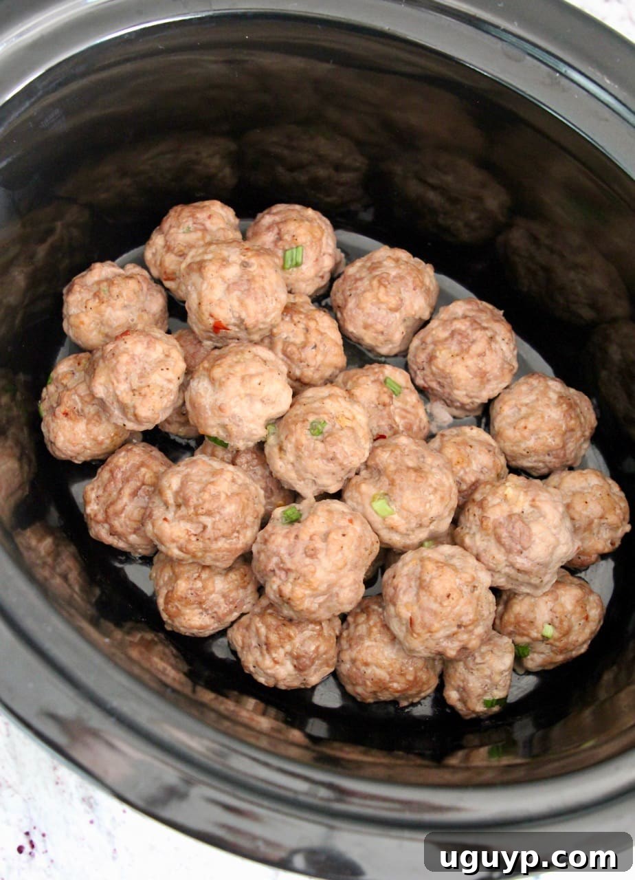 Close-up of Korean meatballs nestled together in a crock pot, coated in sauce.