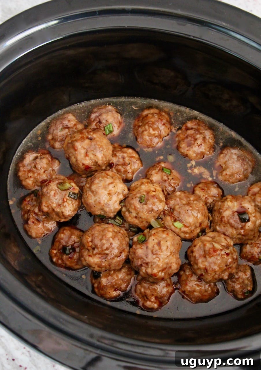 Top-down view of Korean BBQ Meatballs simmering in rich Korean BBQ sauce inside a crock pot.