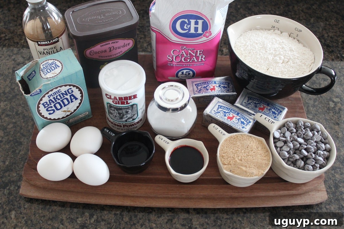 Red Velvet Brookies ingredients laid out on a wooden cutting board, including flour, cocoa powder, sugar, butter, eggs, and chocolate chips.