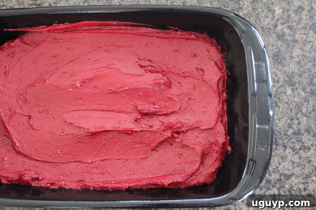 Red velvet brownie batter spread in the bottom of a 9x13 inch baking dish.