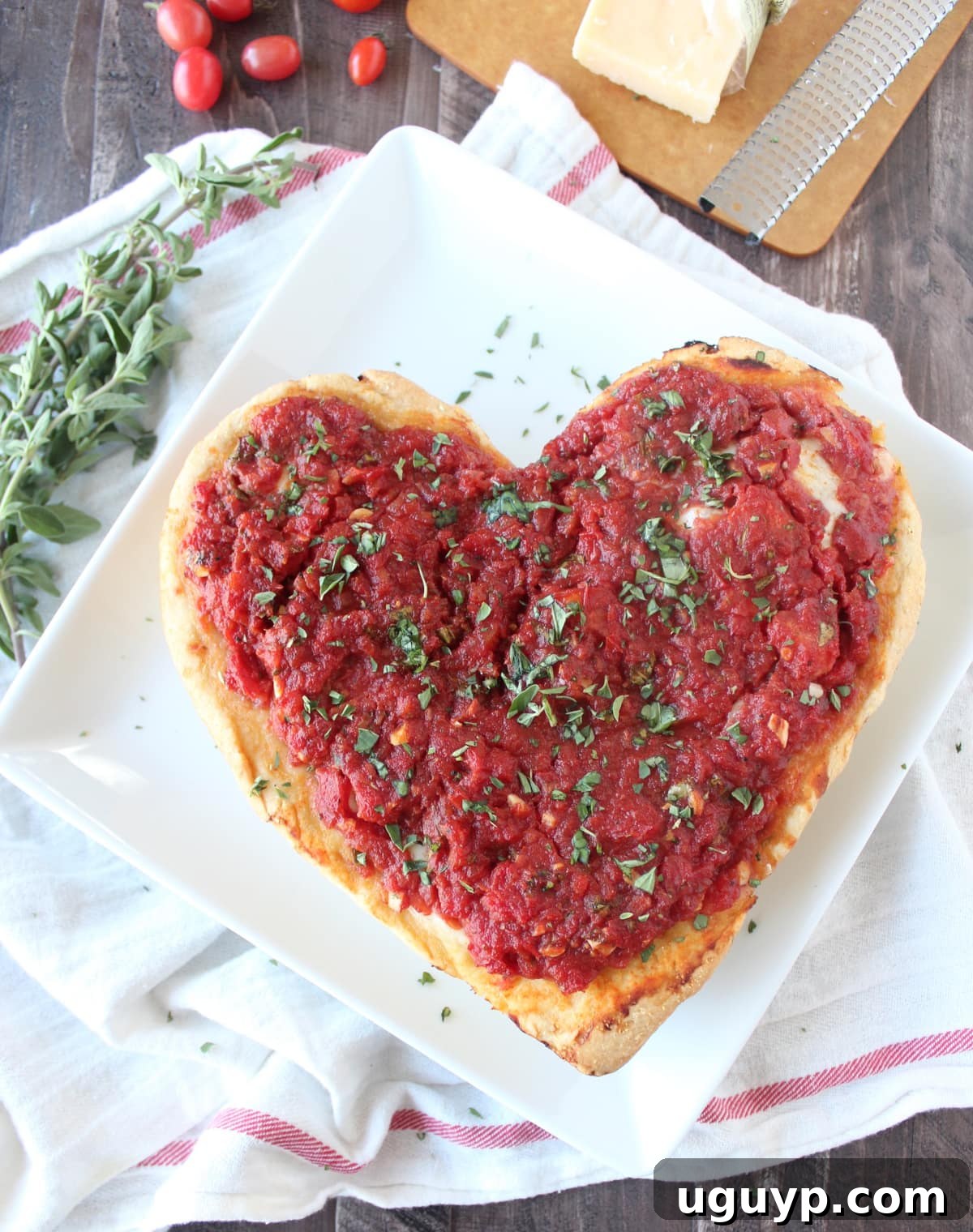 A beautifully baked heart shaped pizza on a white plate, ready to be served.