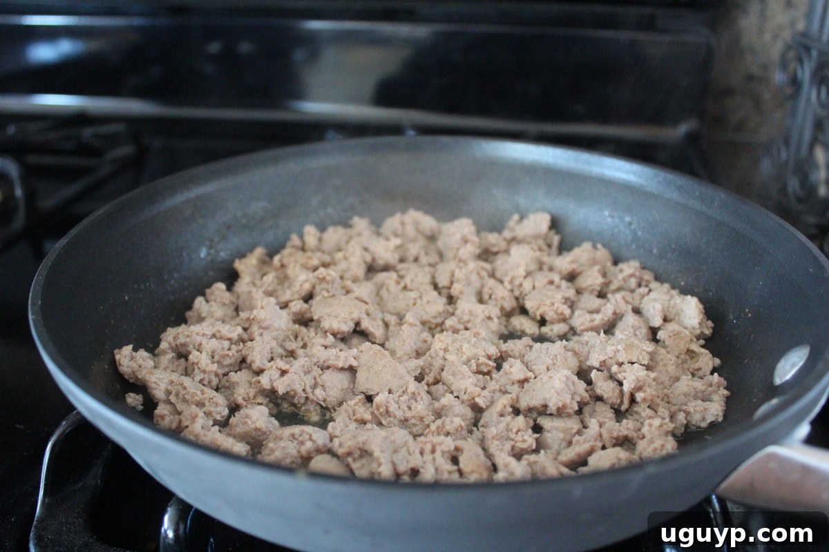 Ground pork cooking in a skillet. 