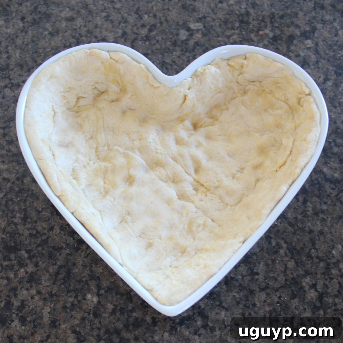 Pizza dough perfectly lining the bottom and sides of a heart-shaped pan.