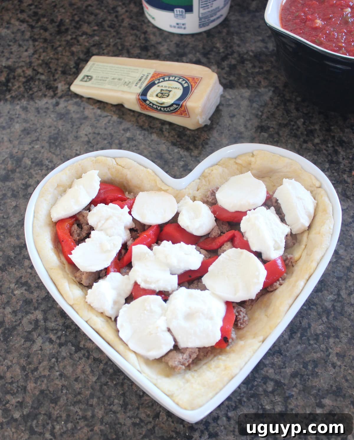 Fresh mozzarella cheese topping sweet Italian sausage and roasted red peppers in a heart-shaped pizza.