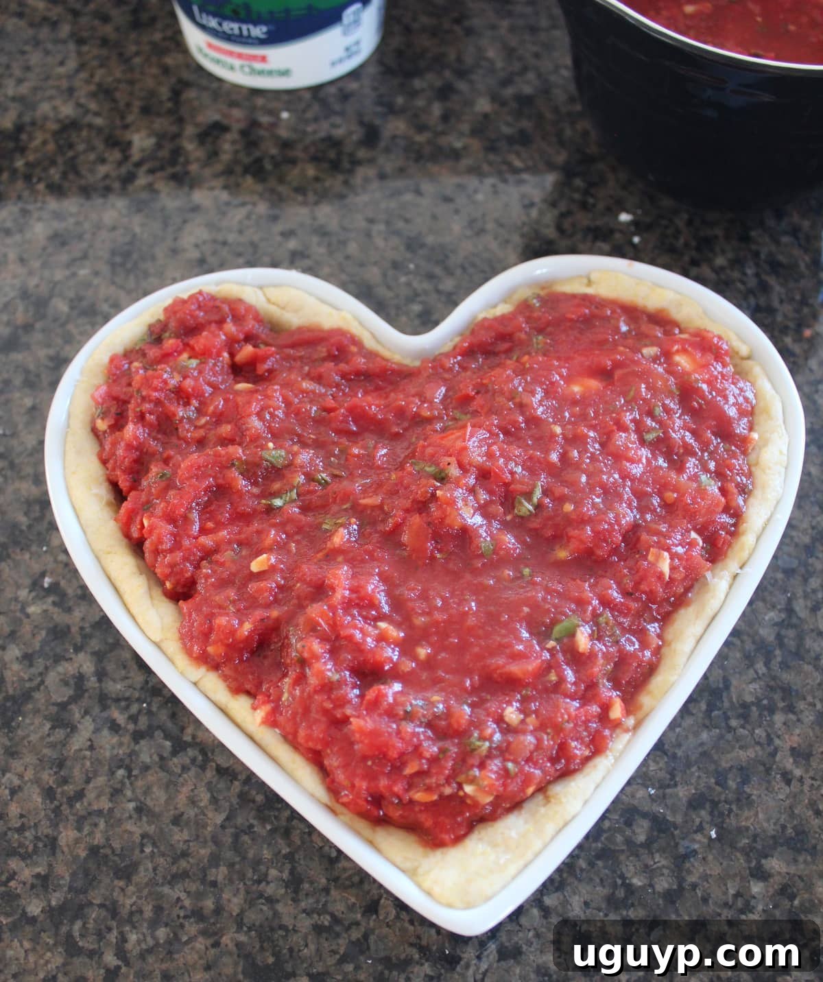 Uncooked Deep Dish Heart Shaped Pizza with all layers of toppings, sauce, and cheese.