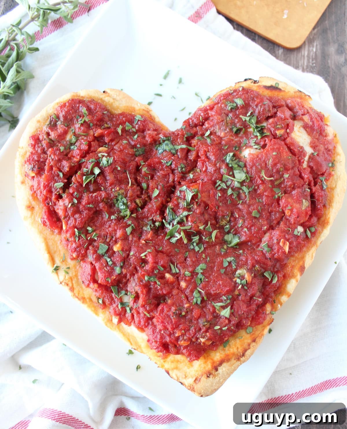 A perfectly baked Deep Dish Heart Shaped Pizza on a white plate, showcasing its golden crust and melted cheese.