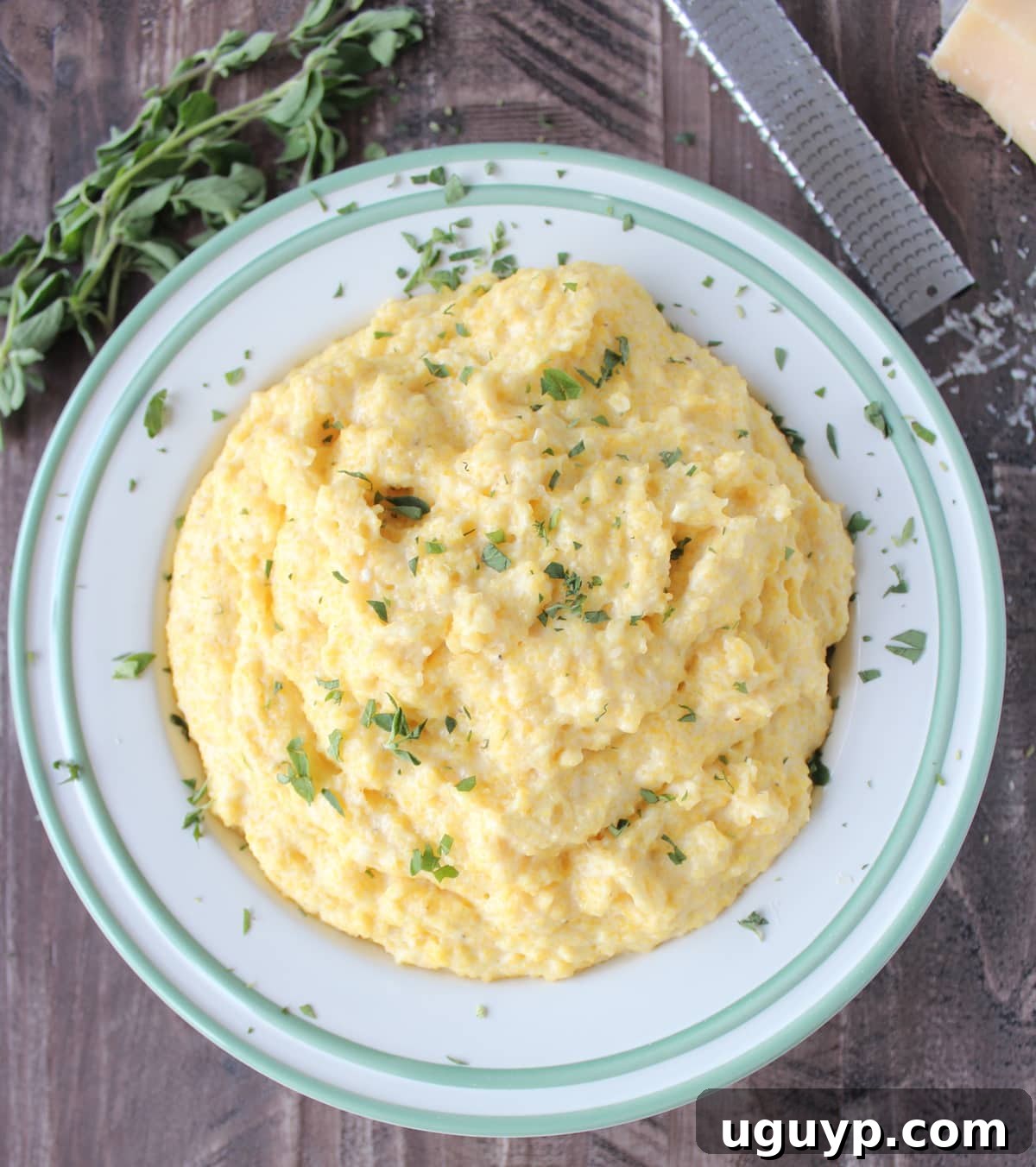 Prepared creamy cheesy polenta in a rustic bowl, garnished with fresh chopped herbs