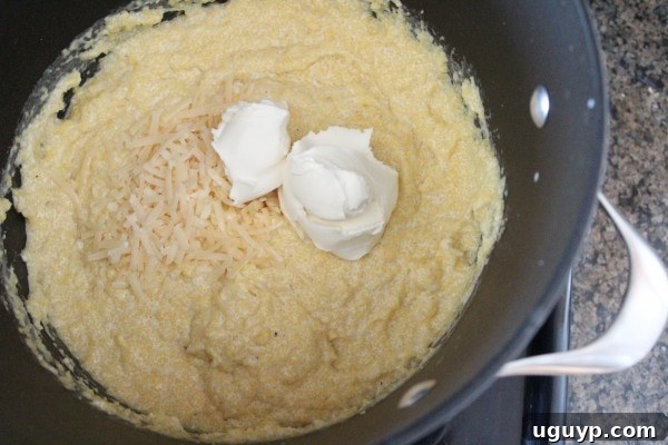 Close-up of creamy polenta in a large pot, with Parmesan and mascarpone cheese being added