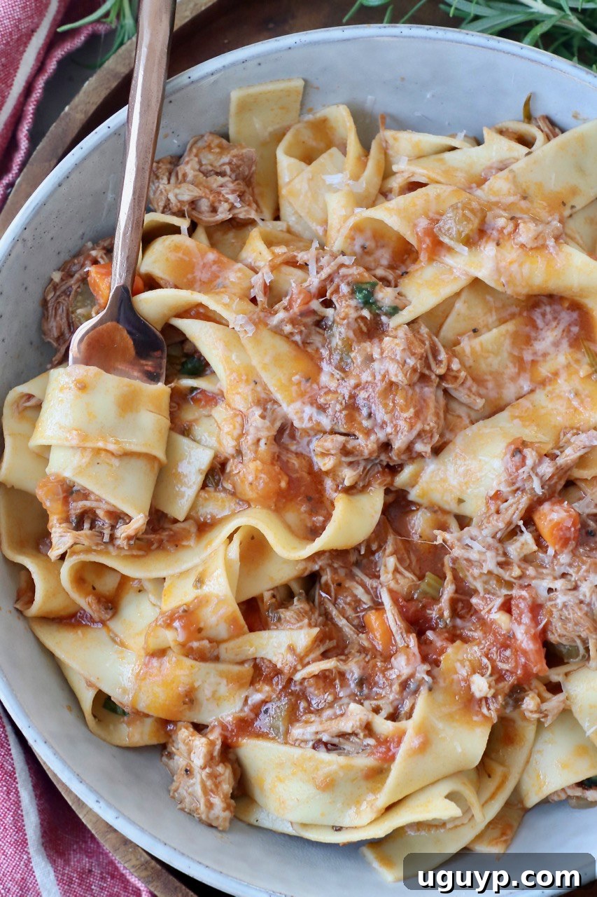 pappardelle pasta tossed with pork ragu in bowl with fork
