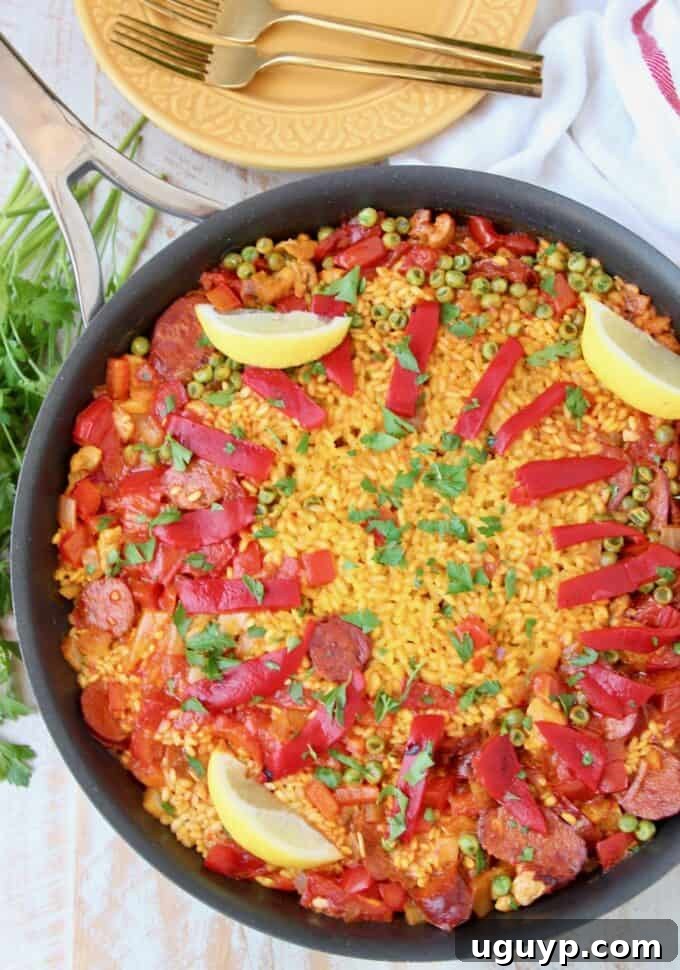 Vibrant Spanish Chicken and Chorizo Paella served in a skillet, garnished with sliced peppers and fresh lemon wedges, ready to be enjoyed.
